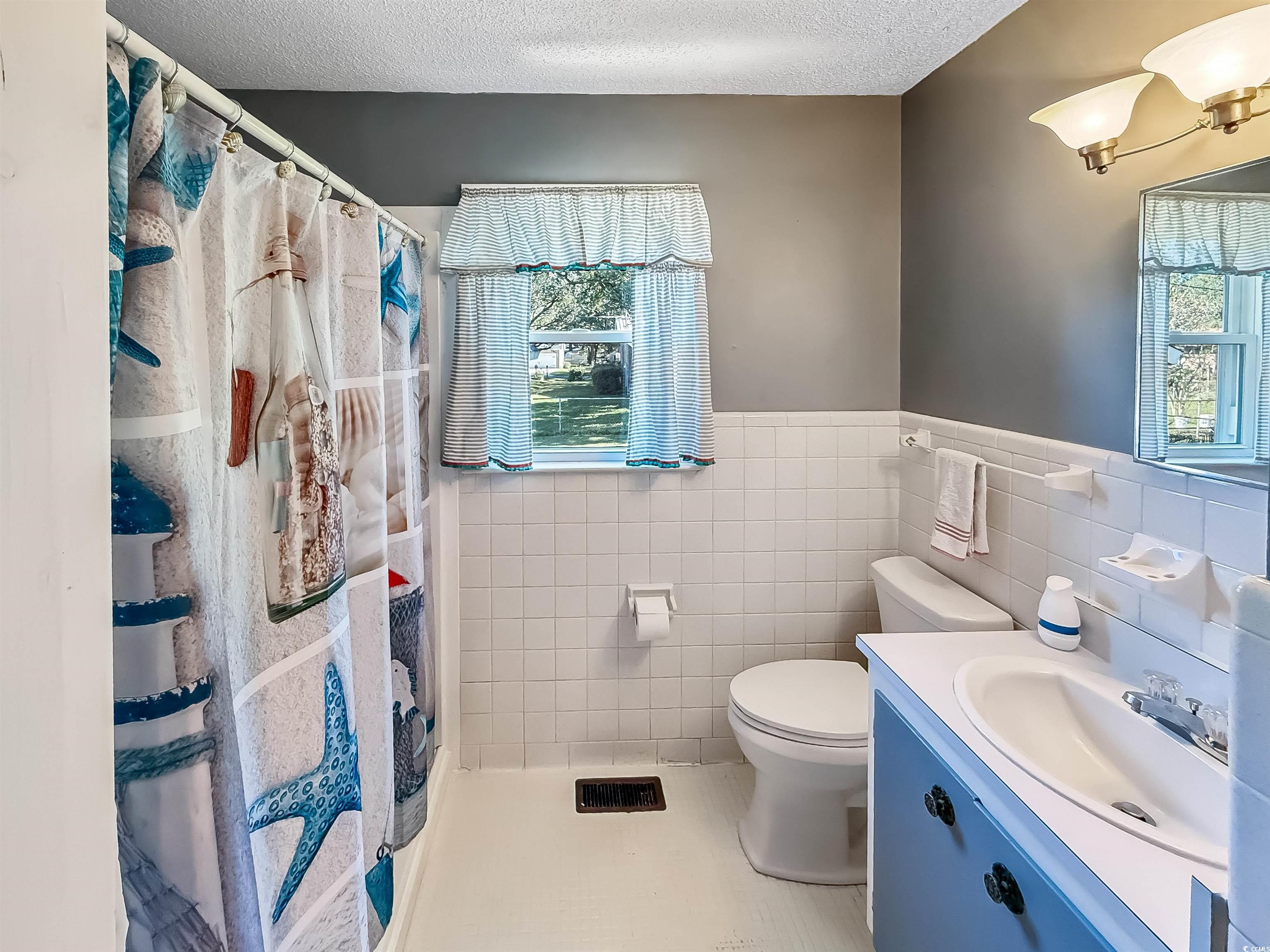 1682 Pickens Street Georgetown, SC 29440 - Photo 29 of 39 Bathroom featuring tile walls, vanity, healthy amount of natural light, a shower with curtain, and light tile patterned flooring