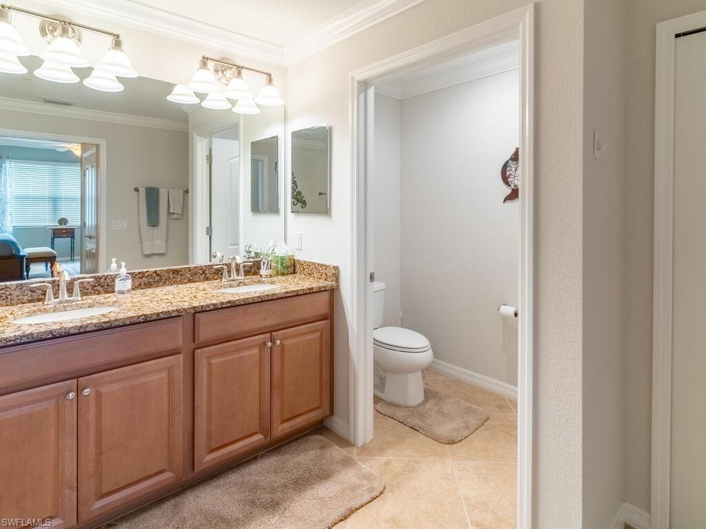 9115 Napoli Court, Unit 101 Naples, FL 34113 - Photo 15 of 49 a spacious bathroom with a granite countertop sink a toilet and a mirror