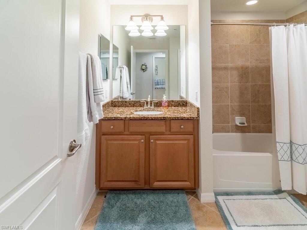 9115 Napoli Court, Unit 101 Naples, FL 34113 - Photo 19 of 49 a bathroom with a granite countertop sink a mirror and a bathtub