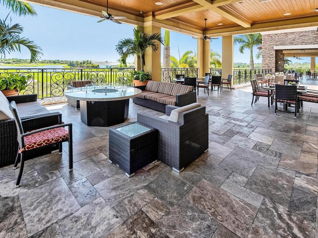 9115 Napoli Court, Unit 101 Naples, FL 34113 - Photo 48 of 49 a living room with patio furniture and a floor to ceiling window next to a yard