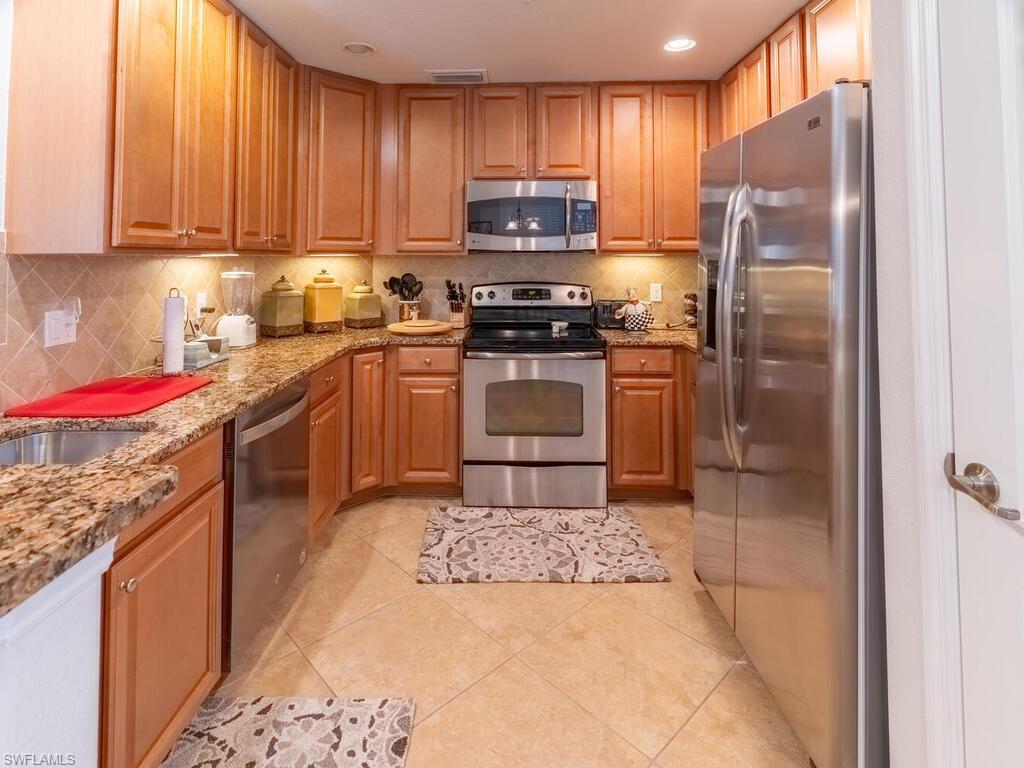 9115 Napoli Court, Unit 101 Naples, FL 34113 - Photo 9 of 49 a kitchen with stainless steel appliances granite countertop a stove a refrigerator and a sink