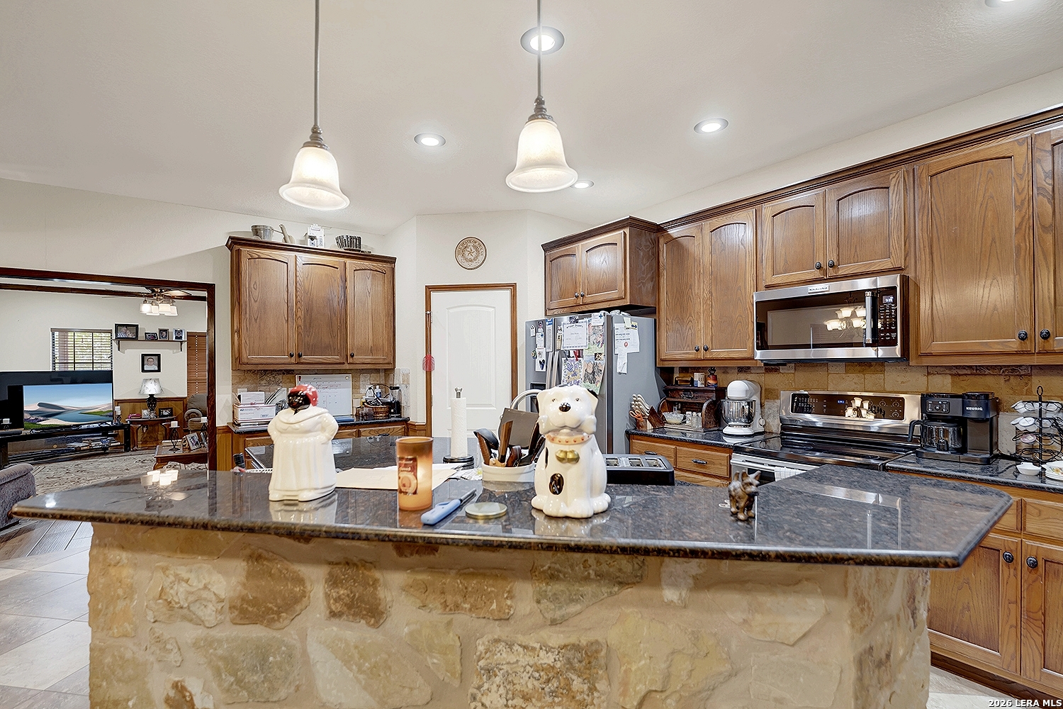 3283 Hartfield Road La Vernia, TX 78121 - Photo 7 of 40 a kitchen with stainless steel appliances granite countertop a sink a stove and a microwave
