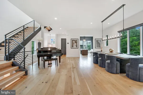 a open kitchen with stainless steel appliances kitchen island granite countertop a stove top oven a dining table and chairs with wooden floor