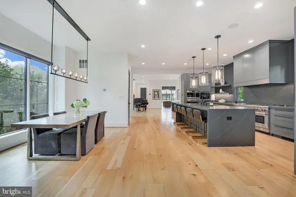 a kitchen with stainless steel appliances kitchen island granite countertop a table chairs and a view of living room