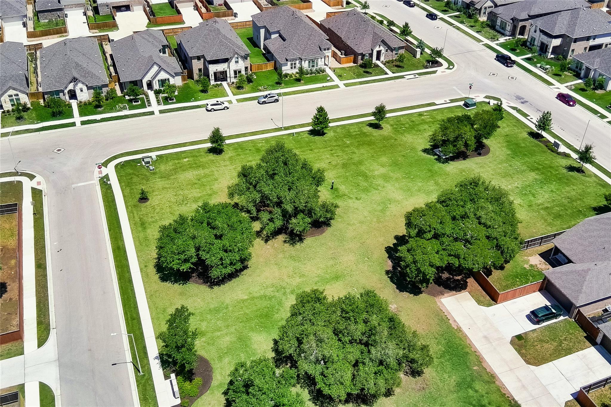 3049 Sage Ranch Drive Leander, TX 78641 - Photo 4 of 23 An aerial perspective showcases a vibrant green community park bordered by modern residential streets.