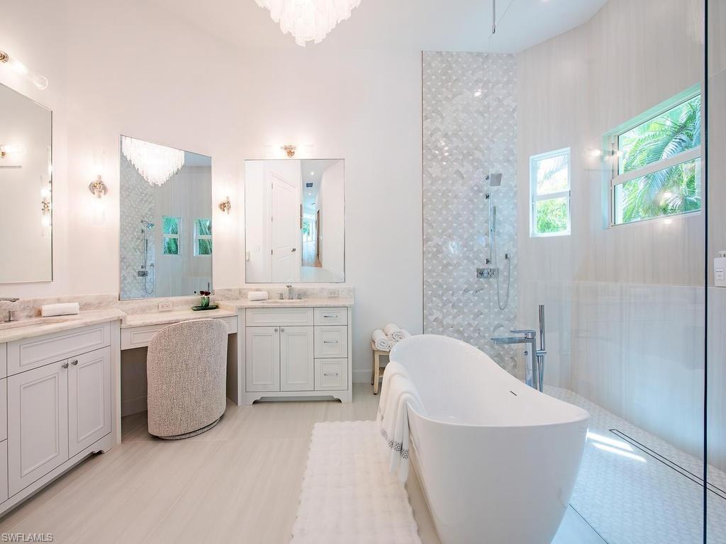 2363 Crayton Road Naples, FL 34103 - Photo 22 of 30 Spacious bathroom featuring a free-standing soaking tub, a walk-in shower with patterned tile, double vanities with stone countertops, and recessed lighting
