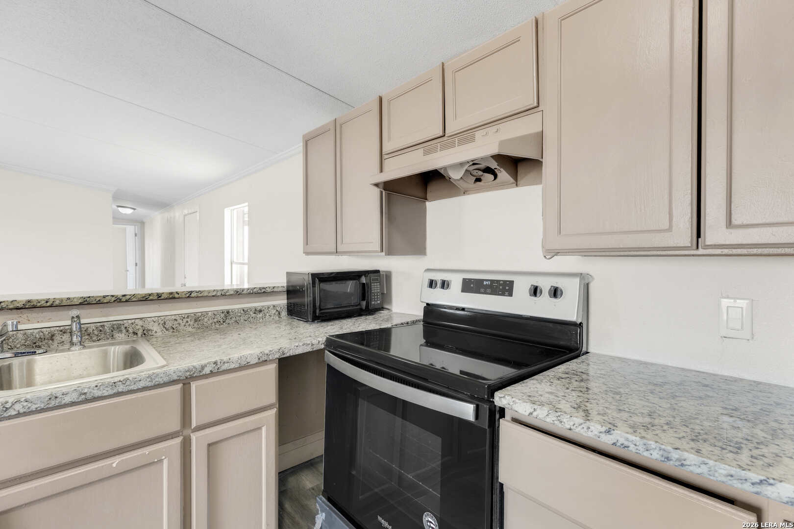 2811 County Road 467 Devine, TX 78016 - Photo 11 of 28 a kitchen with granite countertop a sink dishwasher stove and white cabinets