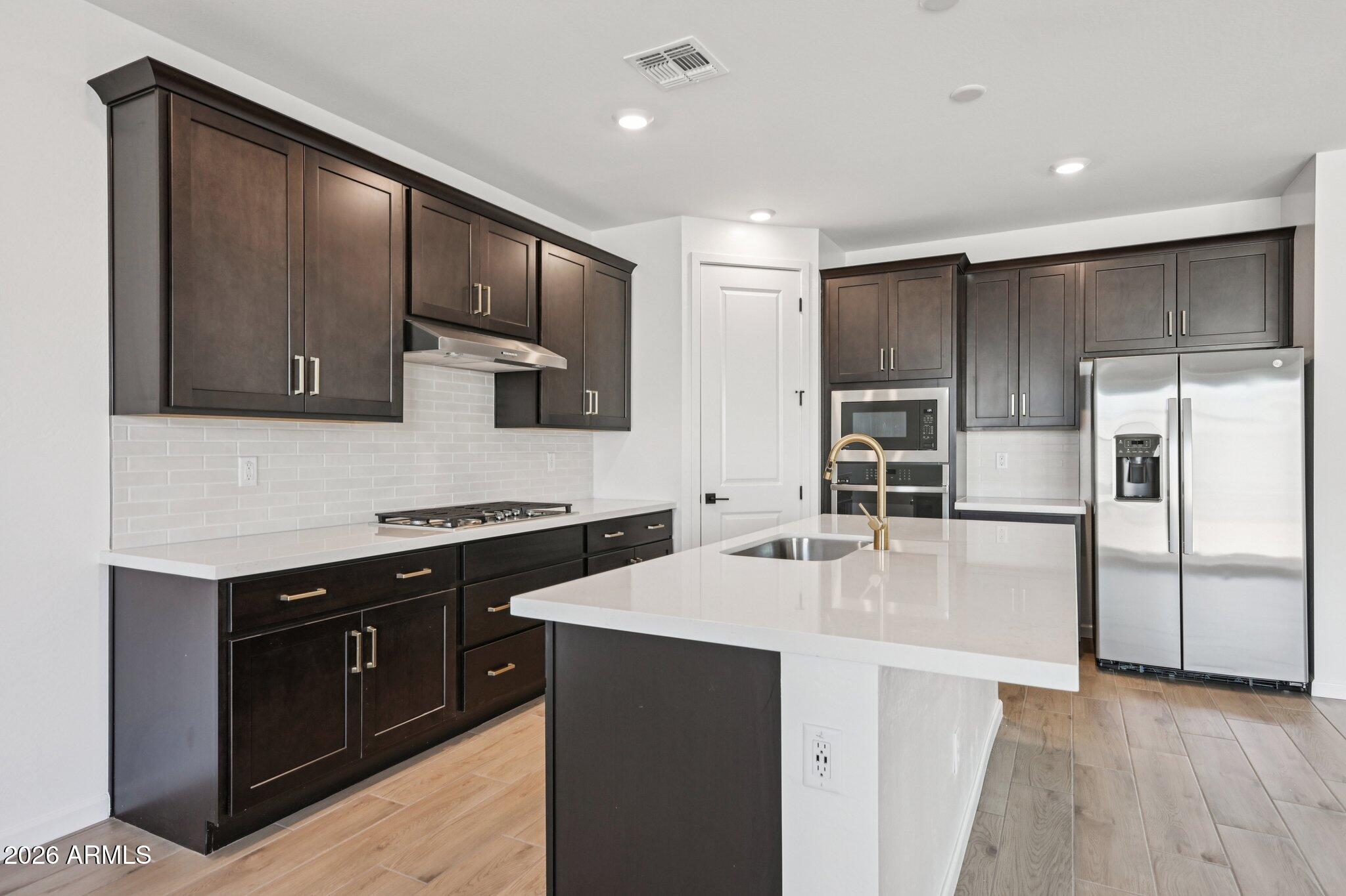 16206 West Red Bird Road Surprise, AZ 85387 - Photo 13 of 35 a kitchen with kitchen island granite countertop stainless steel appliances and wooden cabinets