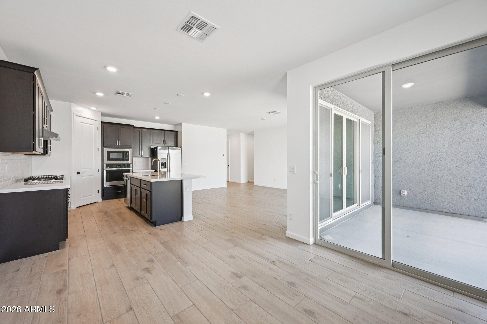 16206 West Red Bird Road Surprise, AZ 85387 - Photo 14 of 35 a large kitchen with stainless steel appliances wooden floor and a refrigerator