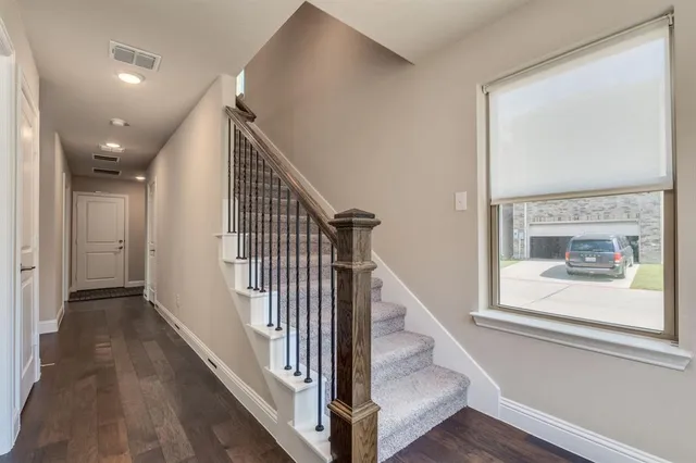 a view of a hallway with wooden floor and staircase
