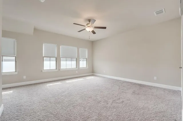 an empty room with windows and ceiling fan
