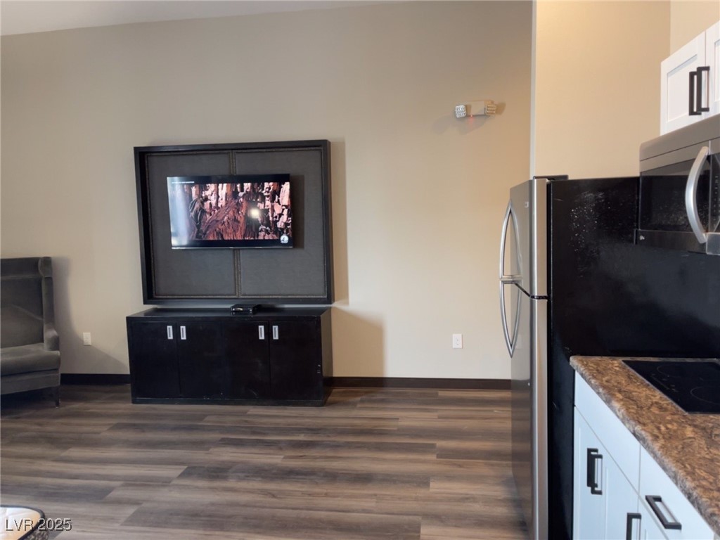 107 South Water Street, Unit 413 Henderson, NV 89015 - Photo 4 of 6 Kitchen featuring dark wood-style floors, dark stone countertops, white cabinets, stainless steel microwave, and black electric cooktop