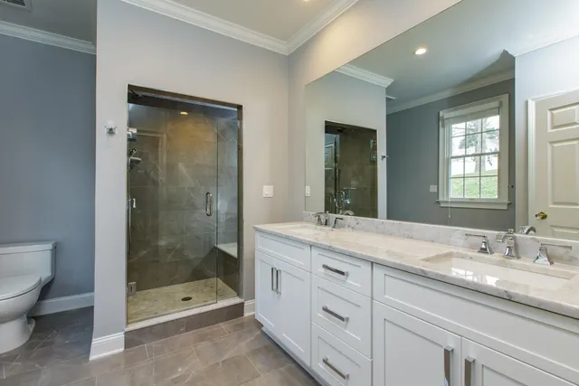 a bathroom with a granite countertop sink a mirror a toilet and shower