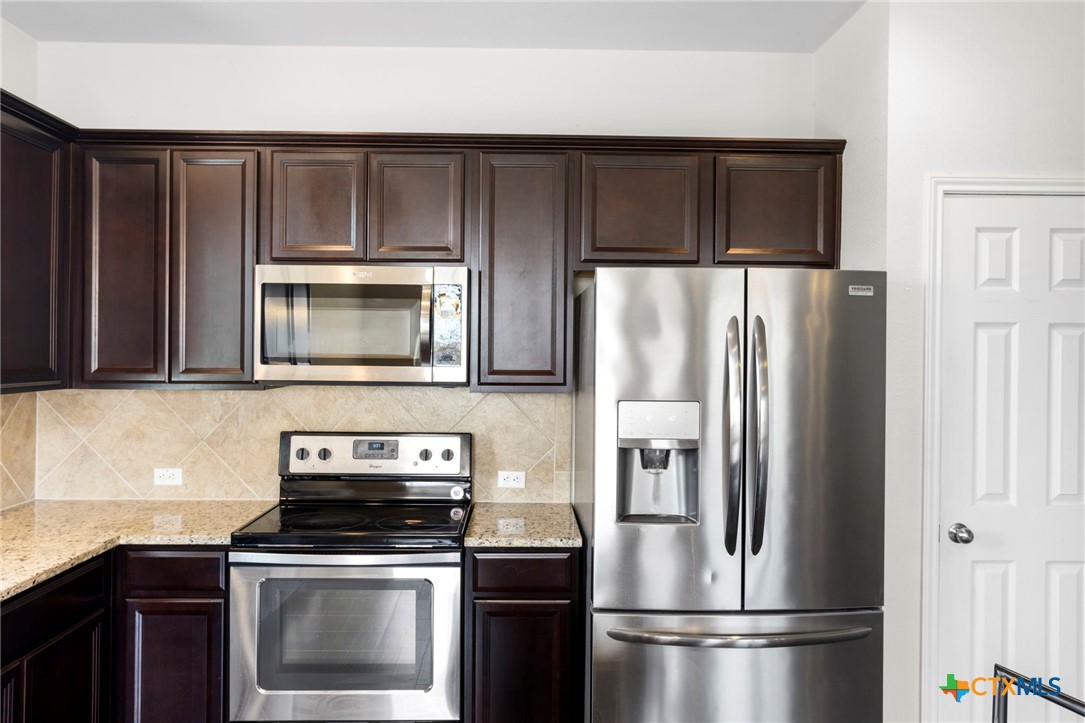 1203 Daffodil Drive Temple, TX 76502 - Photo 12 of 30 a kitchen with wooden cabinets and stainless steel appliances