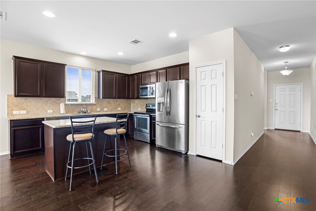 1203 Daffodil Drive Temple, TX 76502 - Photo 14 of 30 a kitchen with stainless steel appliances granite countertop a refrigerator a stove a sink a dining table and chairs with wooden floor