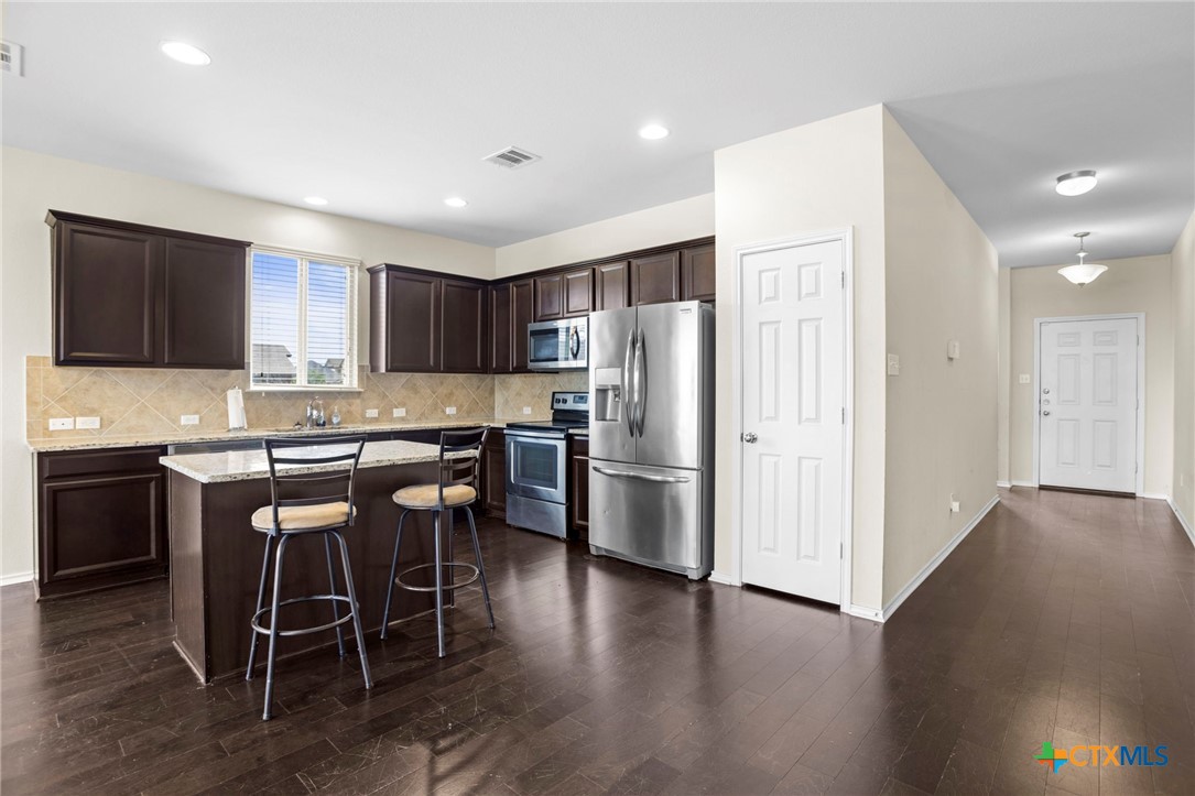 1203 Daffodil Drive Temple, TX 76502 - Photo 8 of 30 a kitchen with stainless steel appliances granite countertop a refrigerator a stove a sink a dining table and chairs with wooden floor