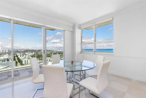 a dining room with furniture large windows and wooden floor