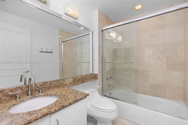 a bathroom with a granite countertop tub shower sink and toilet