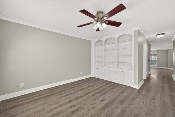 an empty room with wooden floor chandelier fan and windows