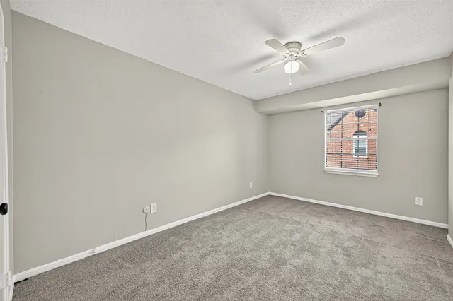 an empty room with a window and a ceiling fan