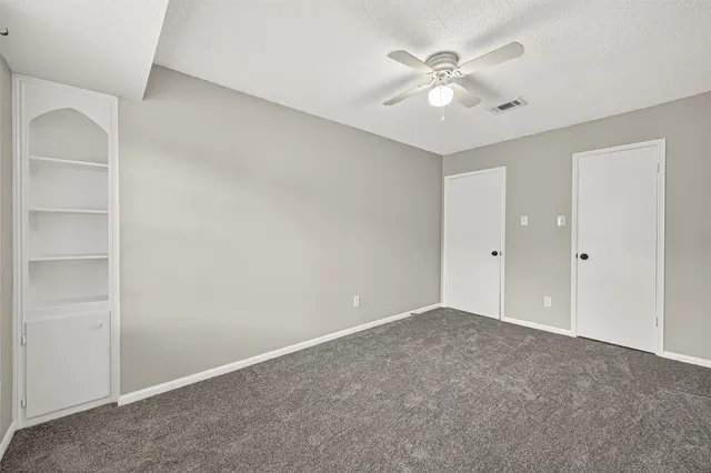 an empty room with closet and ceiling fan