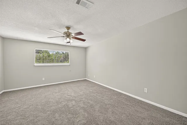 an empty room with a window and a ceiling fan