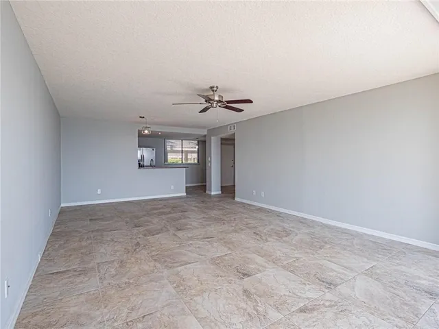 an empty room with a ceiling fan and window