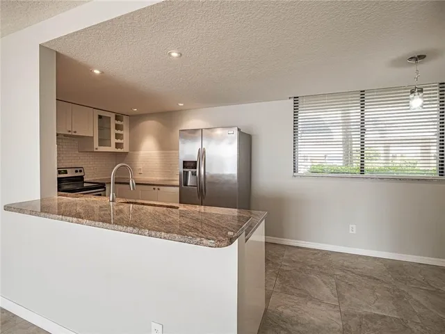 a kitchen with stainless steel appliances granite countertop a sink and a refrigerator
