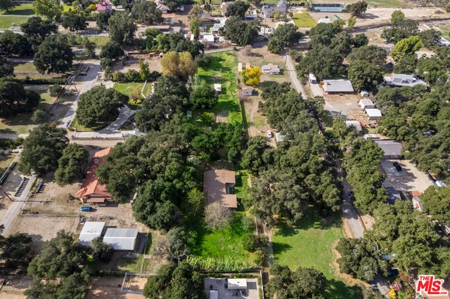 an aerial view of residential houses with outdoor space and trees