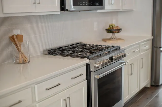 a kitchen with stainless steel appliances granite countertop a sink a stove a microwave and cabinets