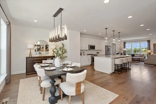 a kitchen with kitchen island granite countertop a table chairs sink and cabinets