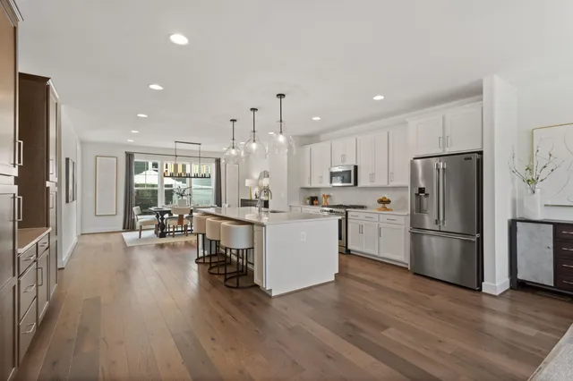 a kitchen with a refrigerator a stove top oven a dining table and chairs with wooden floor