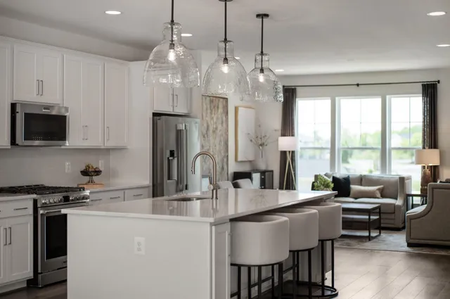 a kitchen with stainless steel appliances granite countertop a stove a refrigerator a sink dishwasher a dining table and chairs with wooden floor