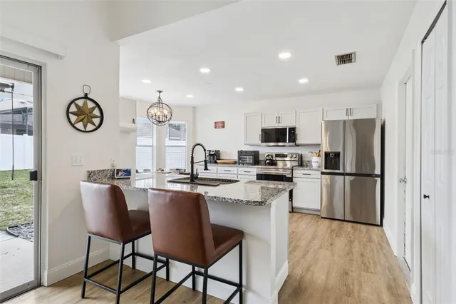 a kitchen with a refrigerator a stove top oven a clock and a window