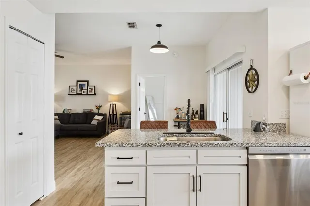a kitchen with granite countertop a sink cabinets and wooden floor