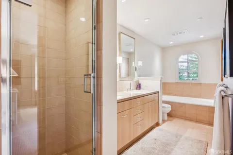 a bathroom with a granite countertop toilet a double vanity sink a mirror and a bathtub