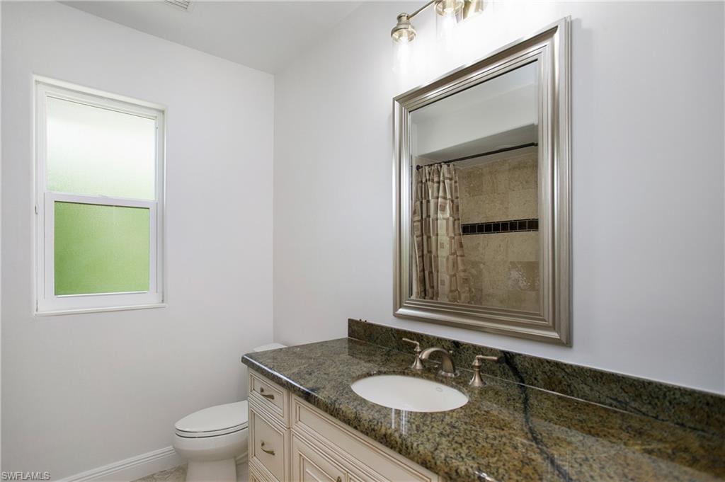 1984 Mission Drive Naples, FL 34109 - Photo 28 of 50 a bathroom with a granite countertop sink toilet and mirror