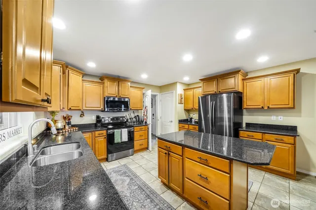 a kitchen with stainless steel appliances granite countertop a sink a stove and refrigerator