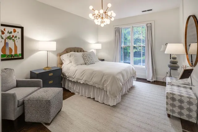 a bedroom with a bed couch chandelier and window