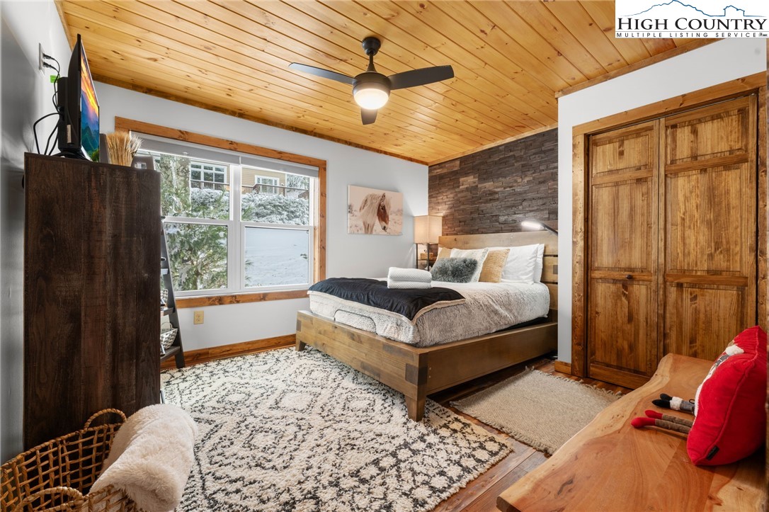 123 St Andrews Road Beech Mountain, NC 28604 - Photo 38 of 47 a bedroom with a bed lamp and a large window with wooden floor