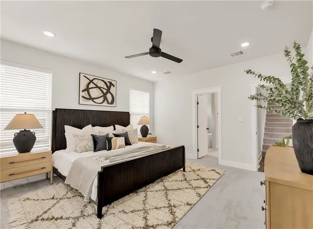 a bed sitting in a bedroom next to a window with a lamp