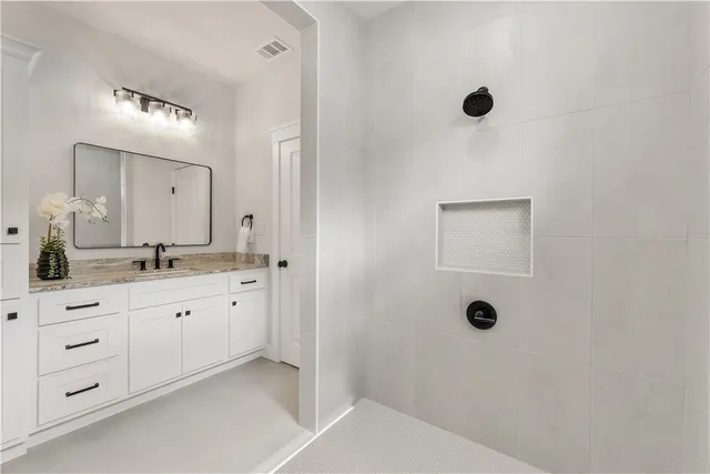 a spacious bathroom with a granite countertop sink a mirror and shower