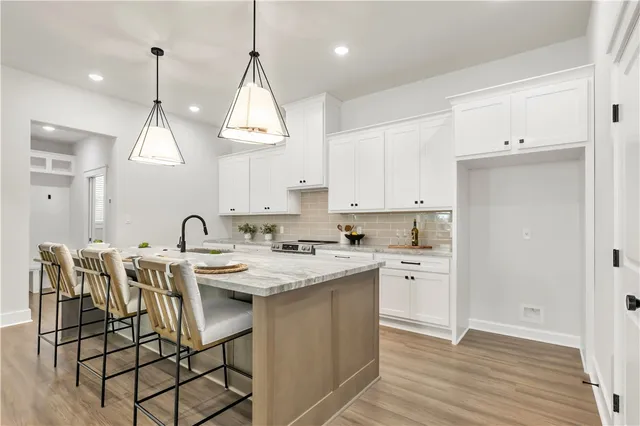 a kitchen with stainless steel appliances granite countertop a dining table chairs sink and cabinets