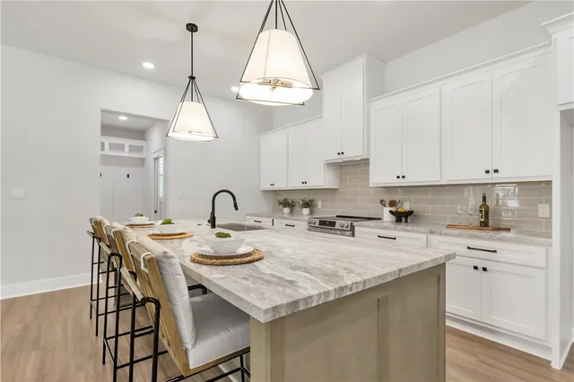 a kitchen with a white cabinets a sink dishwasher a dining table and chairs with wooden floor