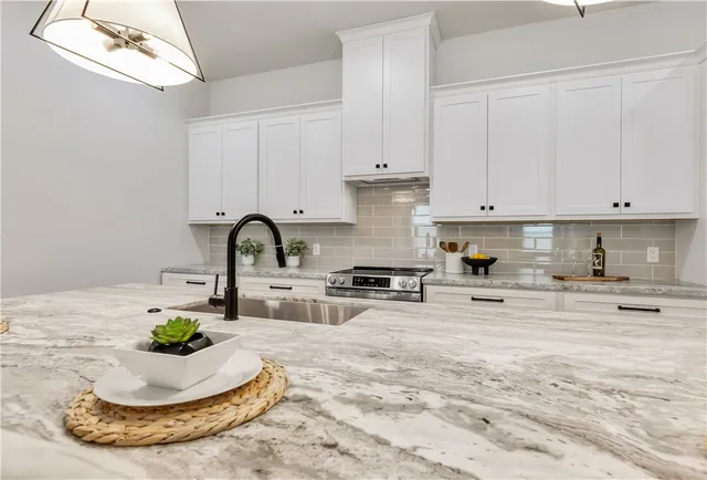 a kitchen with a stove a sink and white cabinets