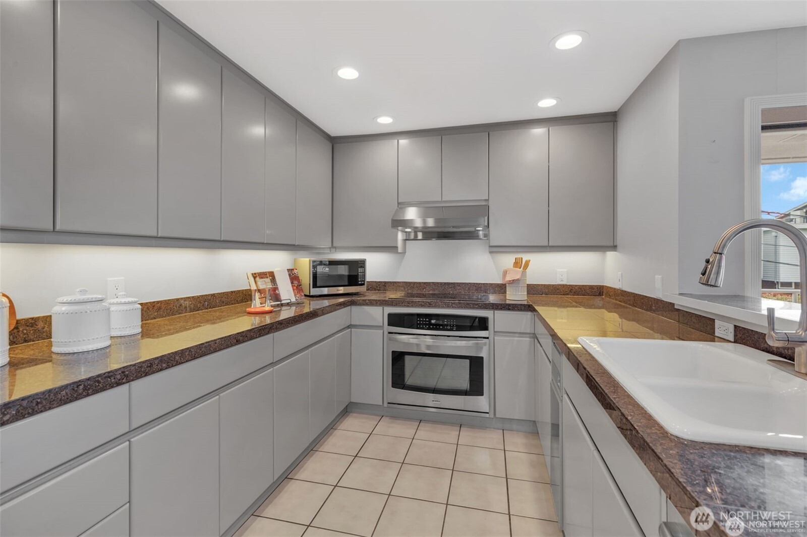 1231 5th Avenue North, Unit 101 Seattle, WA 98109 - Photo 2 of 31 a kitchen with a sink a stove top oven and cabinets