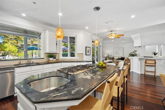 a kitchen with stainless steel appliances granite countertop a sink a stove and a wooden cabinets