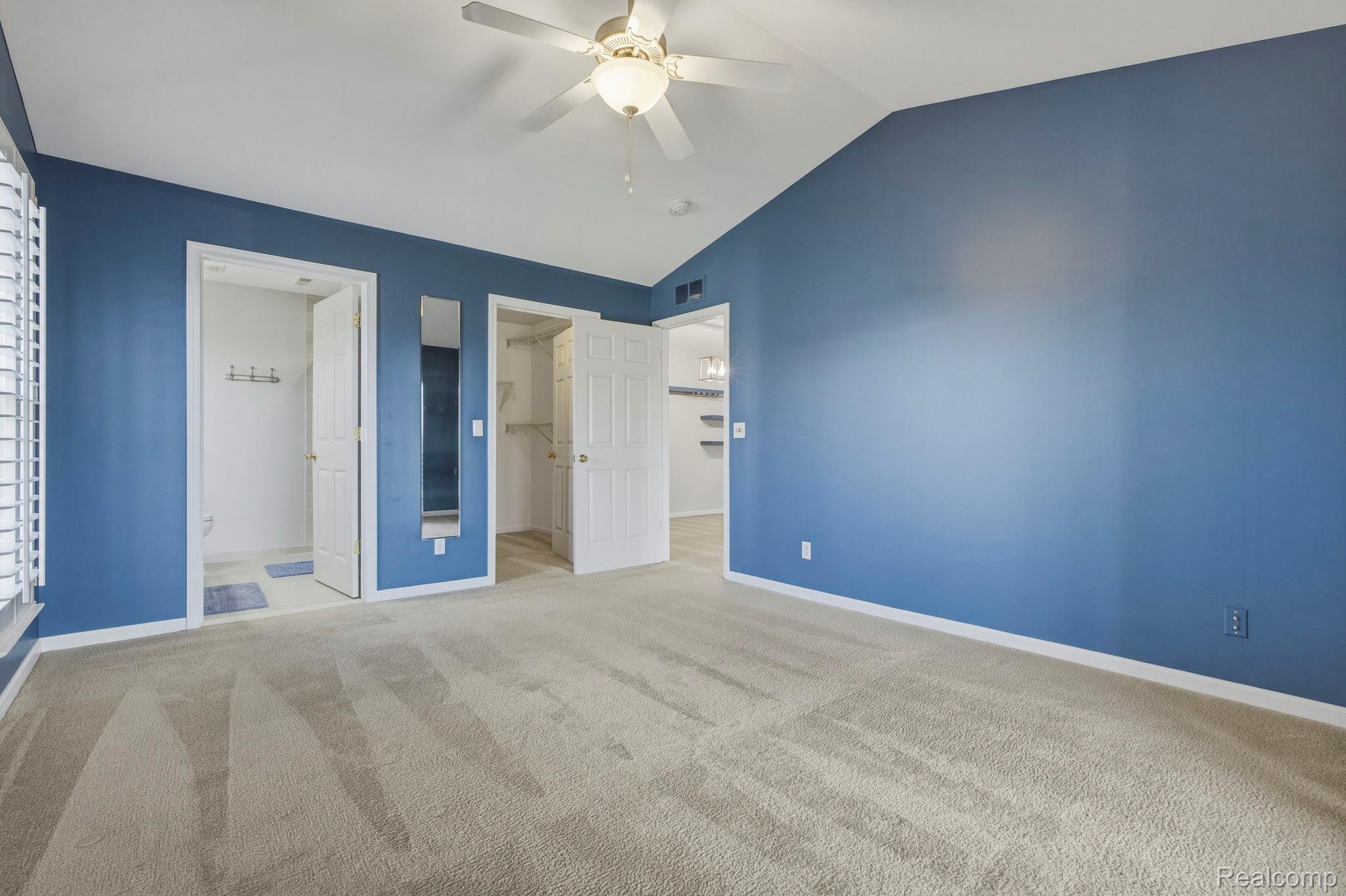 1905 Flagstone Circle Rochester, MI 48307 - Photo 21 of 33 Vaulted ceiling, ceiling fan with integrated lighting, window with white plantation shutters, walk-in closet with shelving, and light-toned carpet flooring