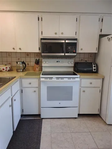 a kitchen with white cabinets and white appliances