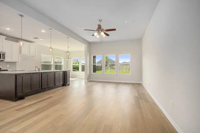a view of an empty room with a kitchen and wooden floor